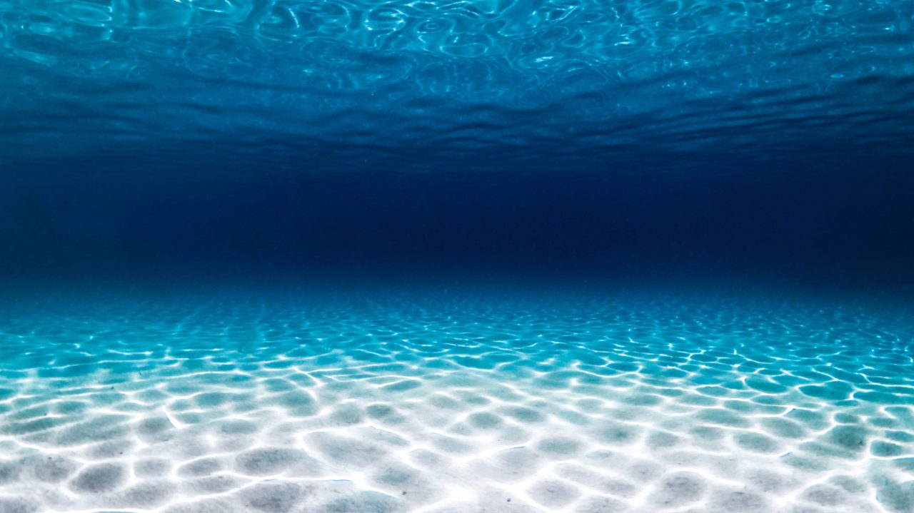 Sunlight and a diver in deep blue water